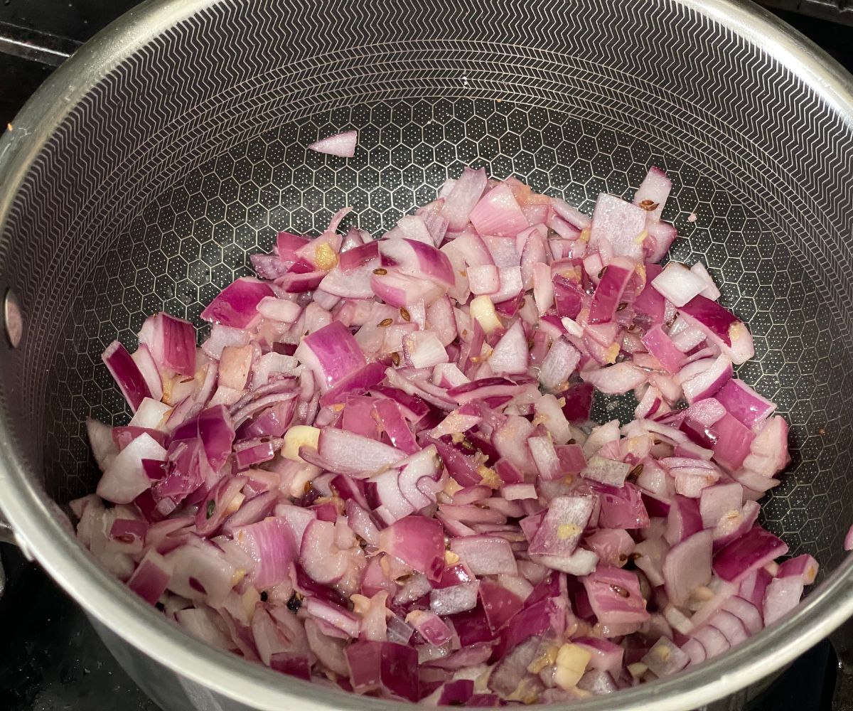 A pan is with ginger garlic and chopped onions over the heat.