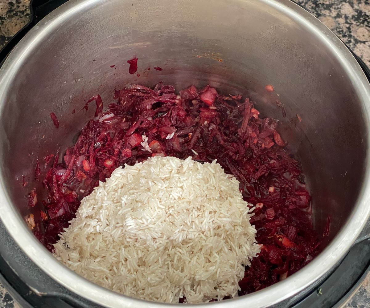 A pot is with spices, beets and rice on cooking mode.
