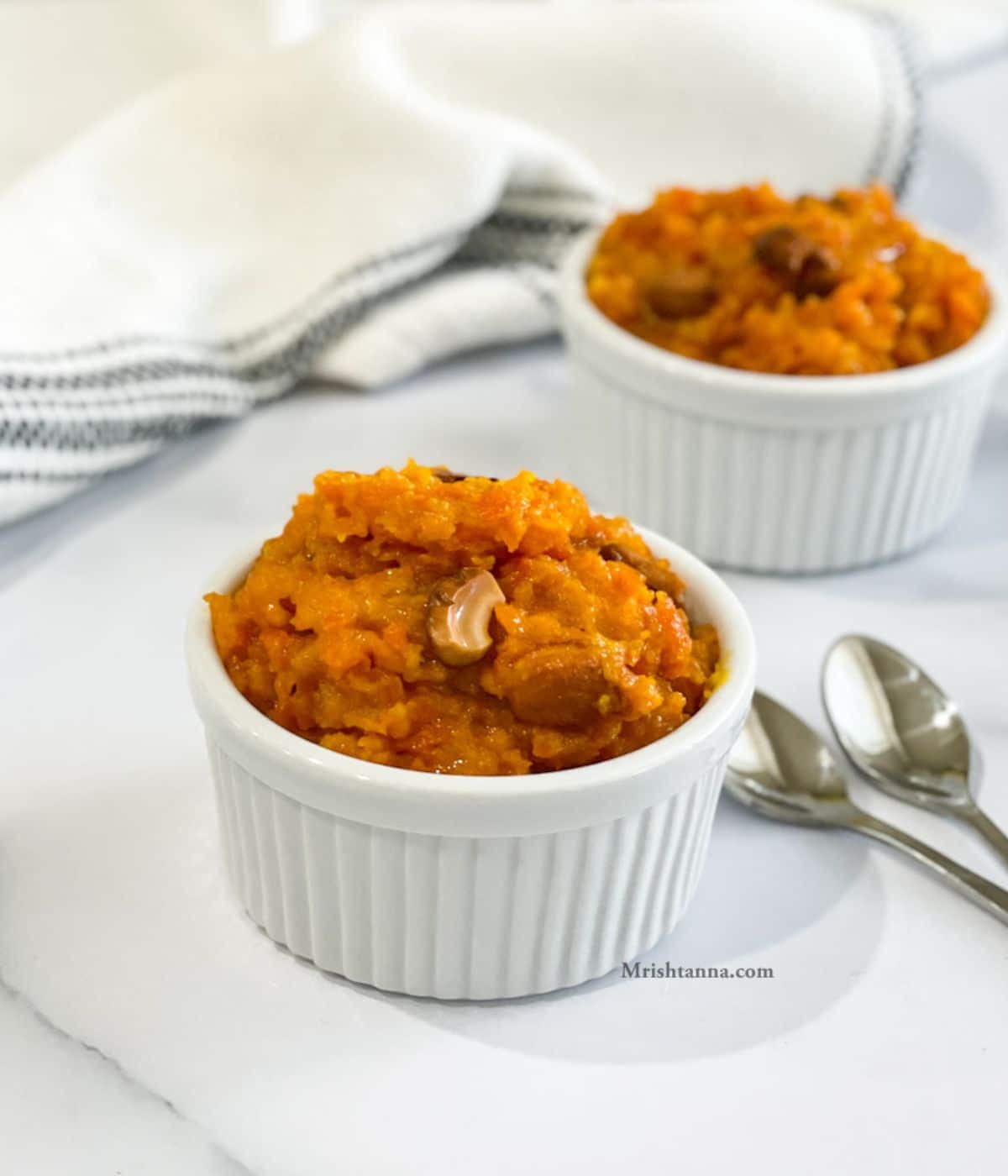 Bowl of instant pot carrot halwa is topped with nuts.