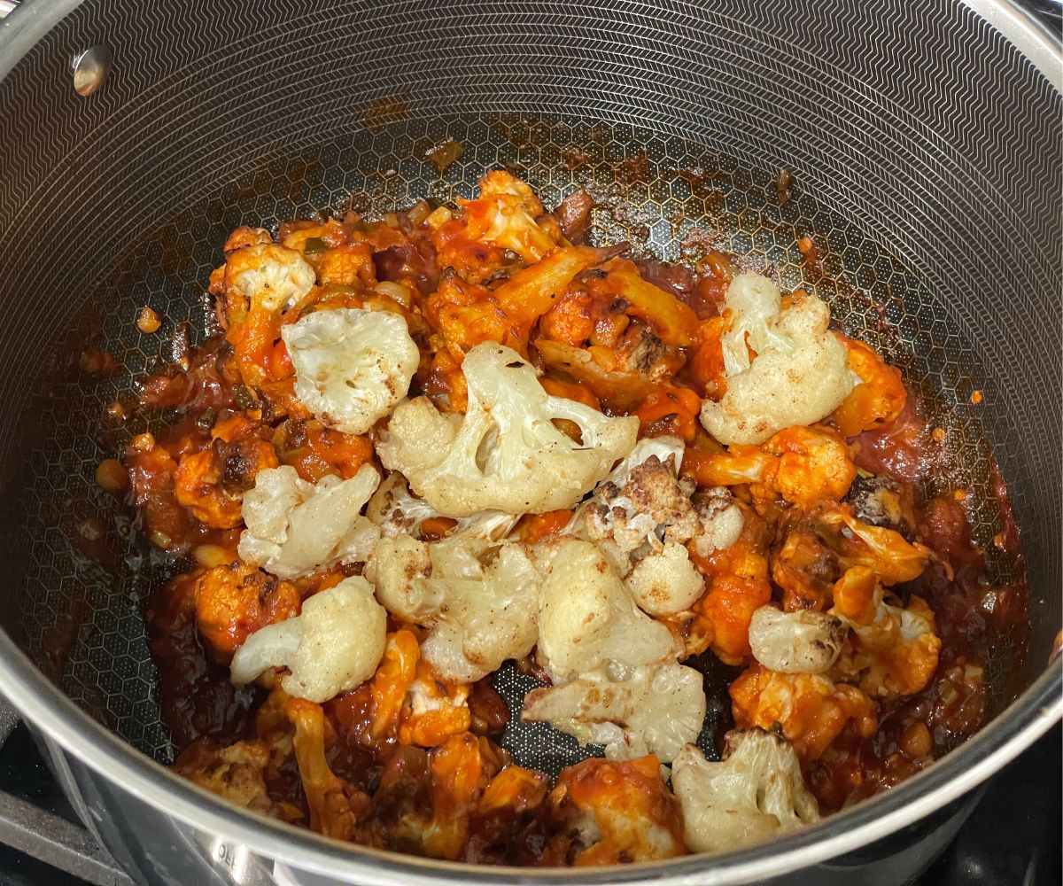 A pan is with lasuni gobi sauce and tossed with air fried cauliflower.