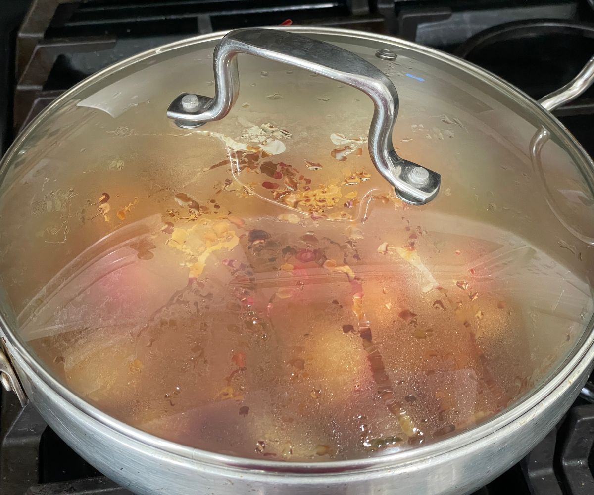 A covered pot is with radish curry over the heat.