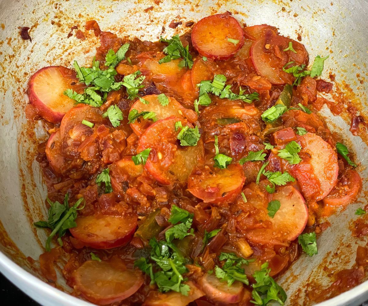 A kadai is with radish curry topped with cilantro.