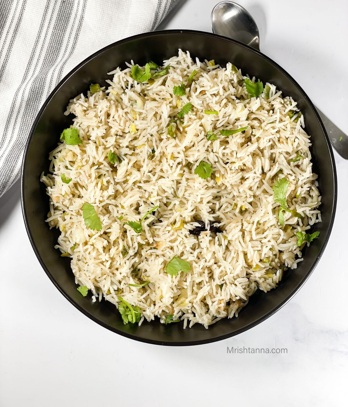 A plate of green onion rice is on the table.