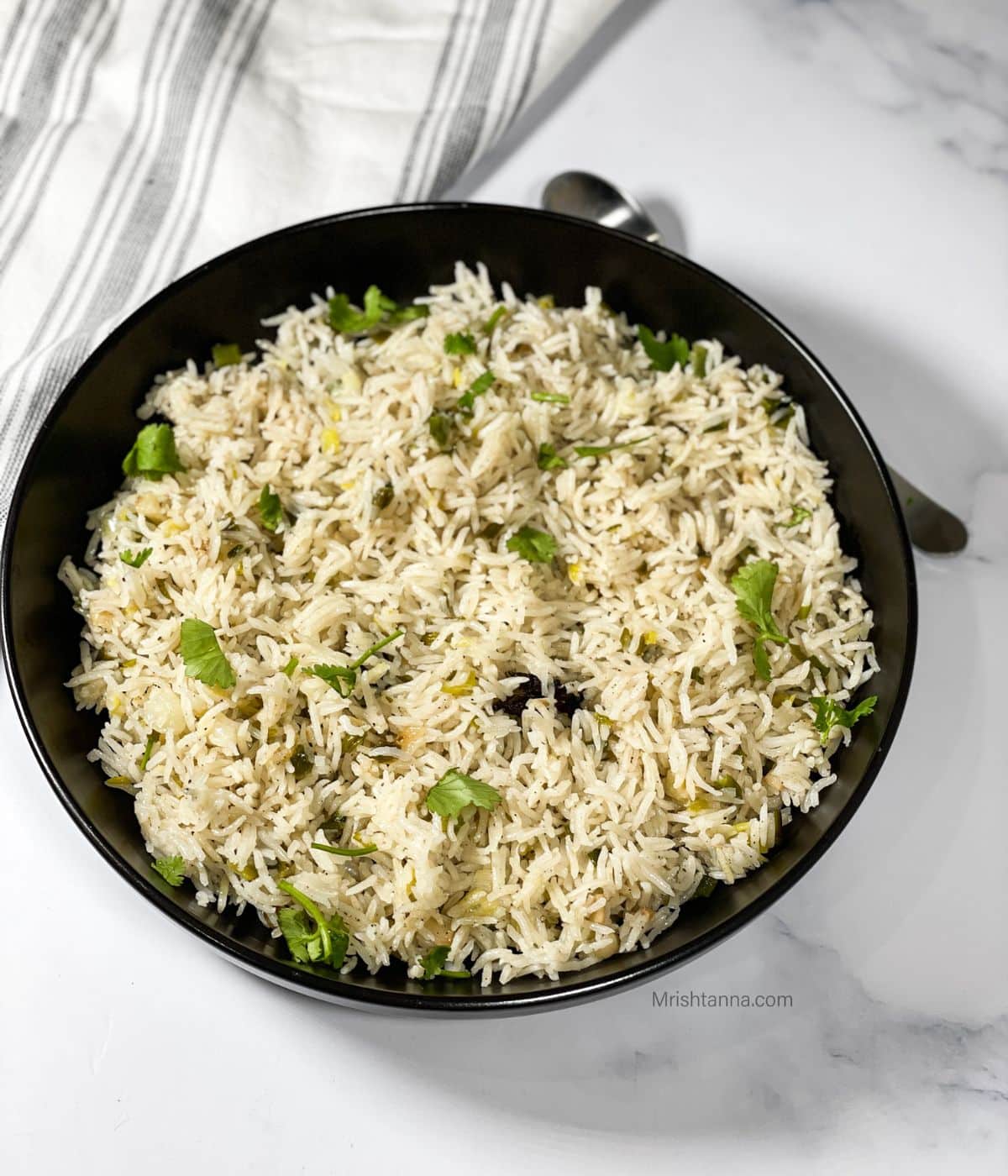 A plate is with green onion rice topped with cilantro.