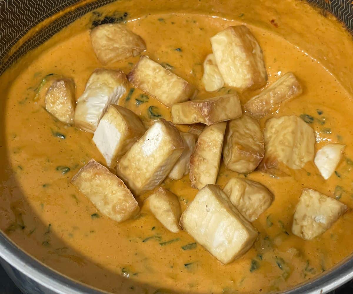 A pot with curry sauce and tofu.