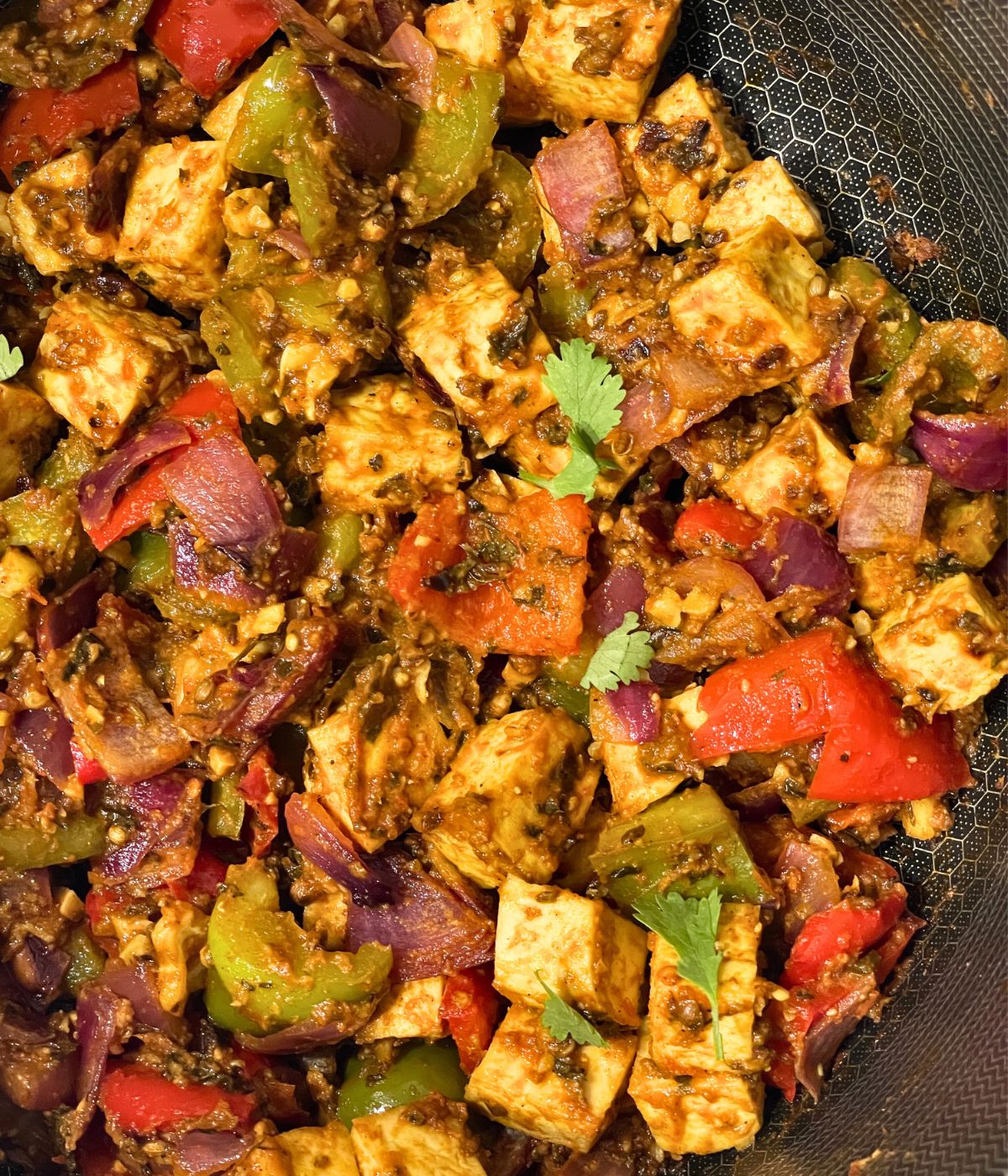 A pan is with Indian stir fry with tofu and bell peppers.