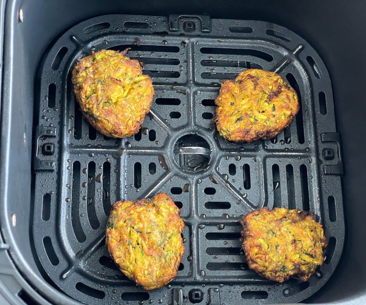 Air fryer basket is with fried zucchini fritters.