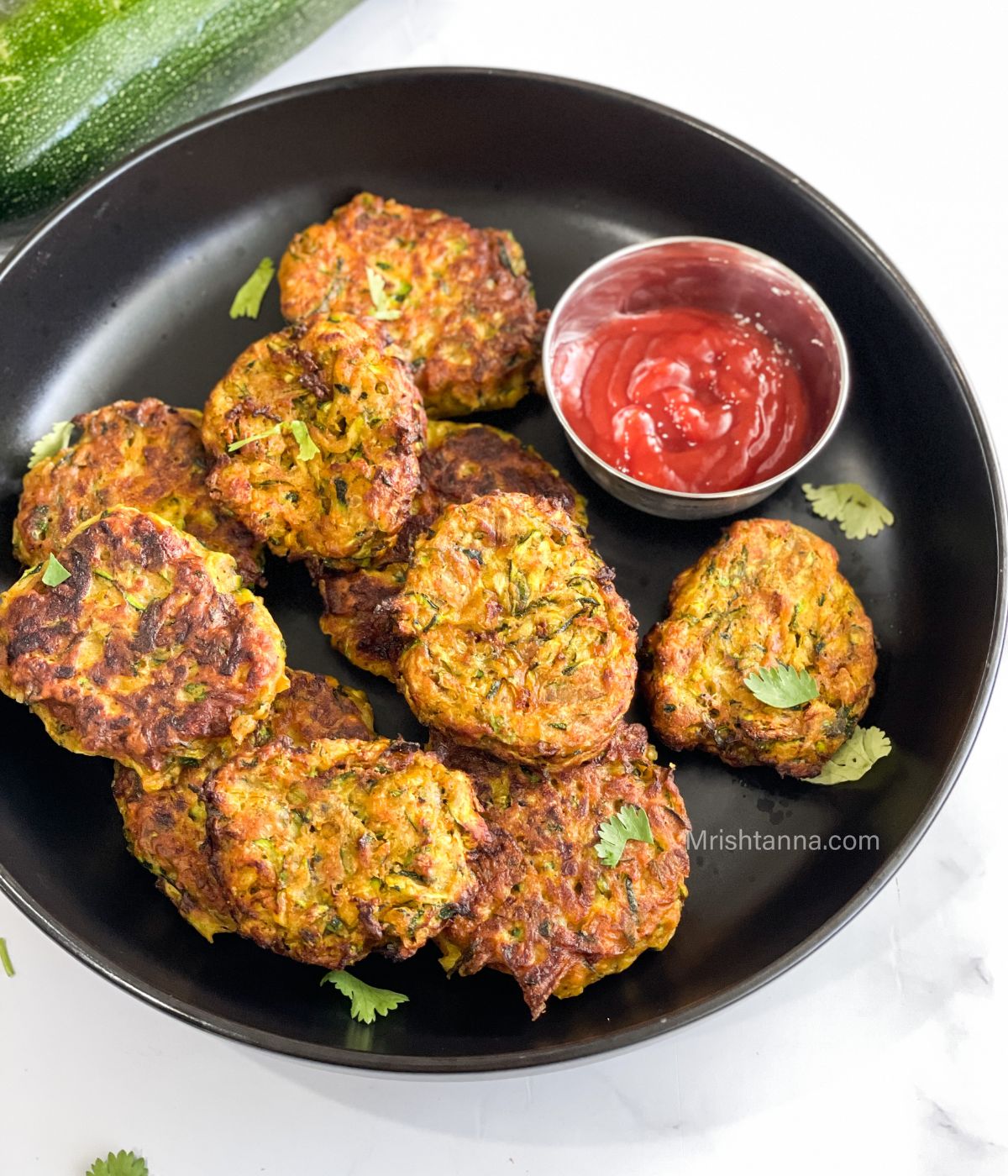 A plate of zucchini fritters is on the table.