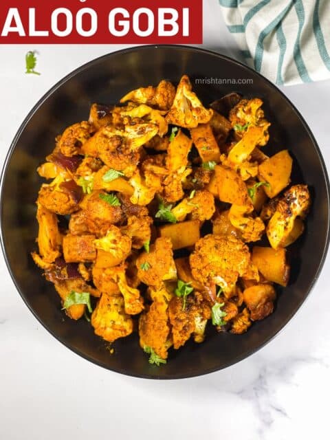 A bowl of roasted cauliflower and potatoes on the surface.