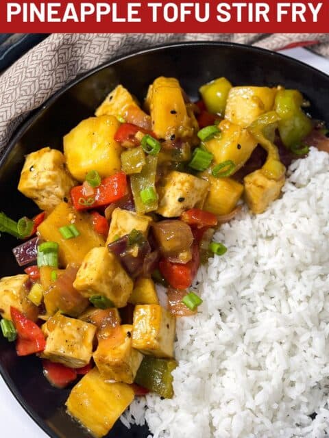 A plate of pineapple tofu stir fry and rice is under the napkin.