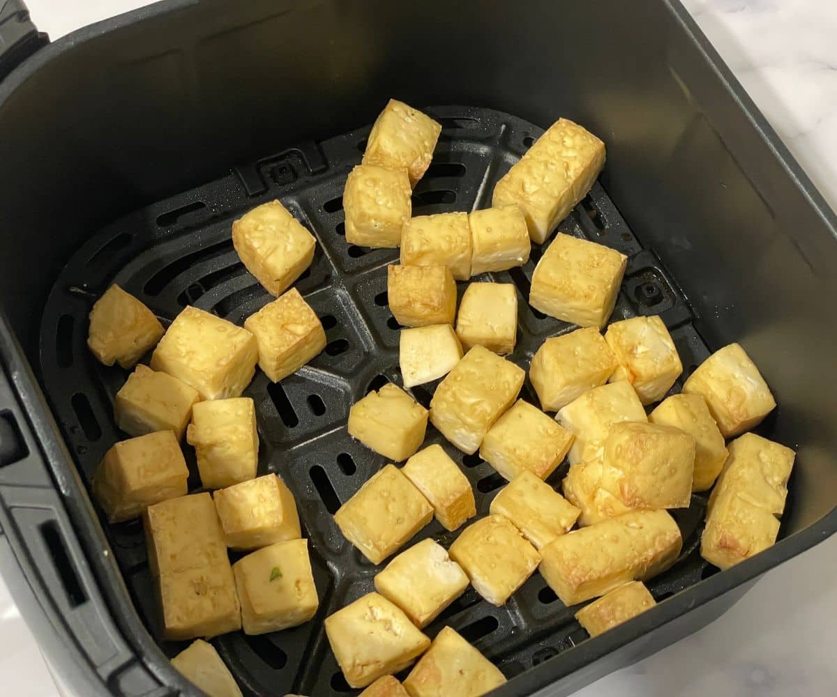 Air fried tofu is in the air fryer basket.