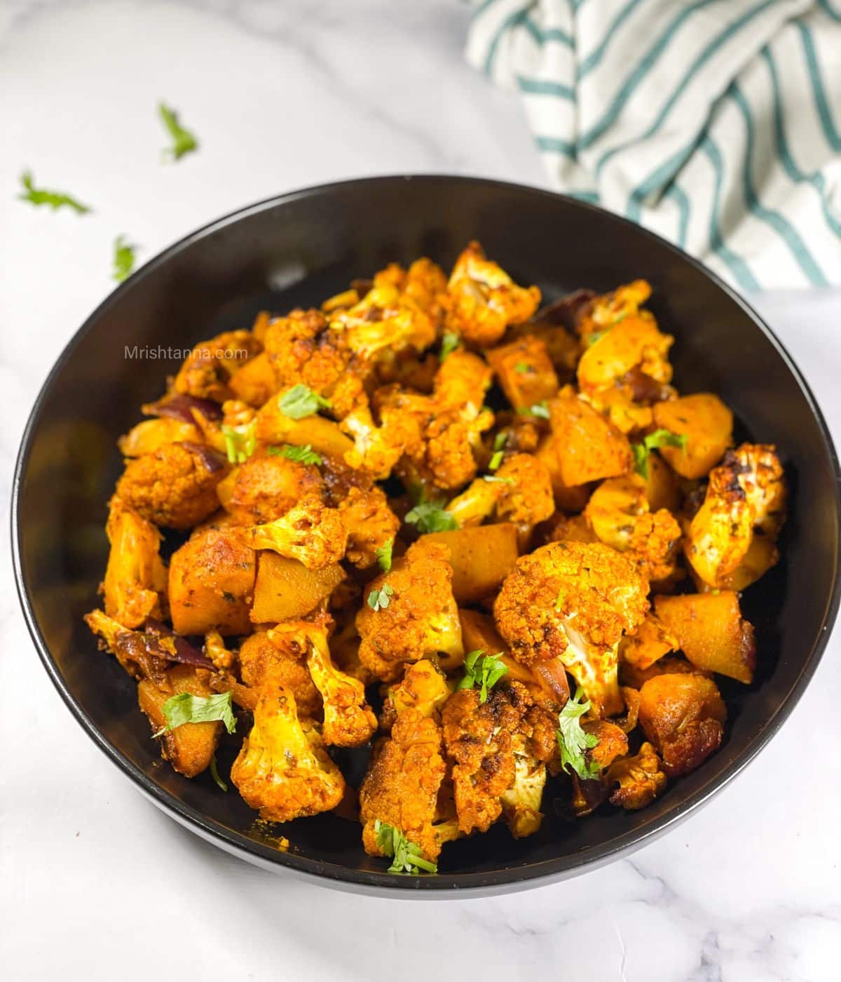 A bowl of aloo gobi is on the table.