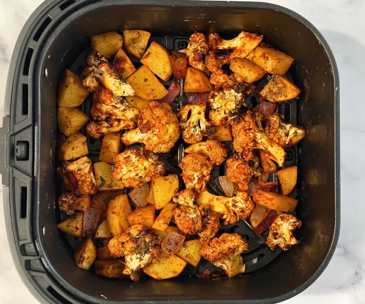 Air fryer basket is filled with roastd aloo gobi.