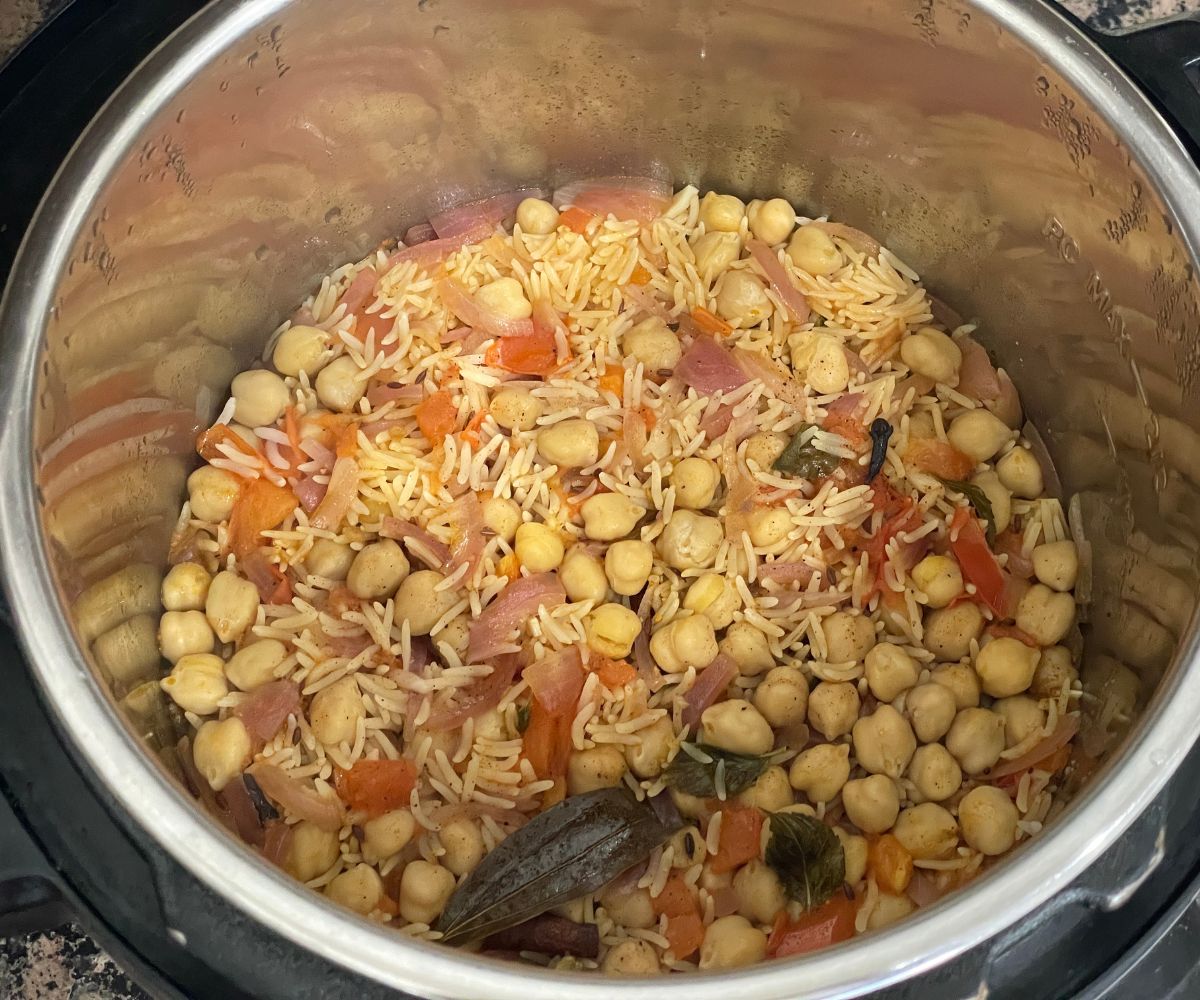 An instant pot is with cooked chickpea rice.