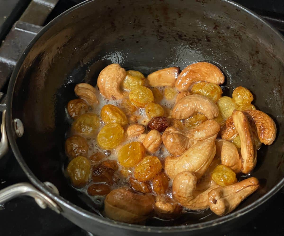 A pan is with roasted nuts and raisins.