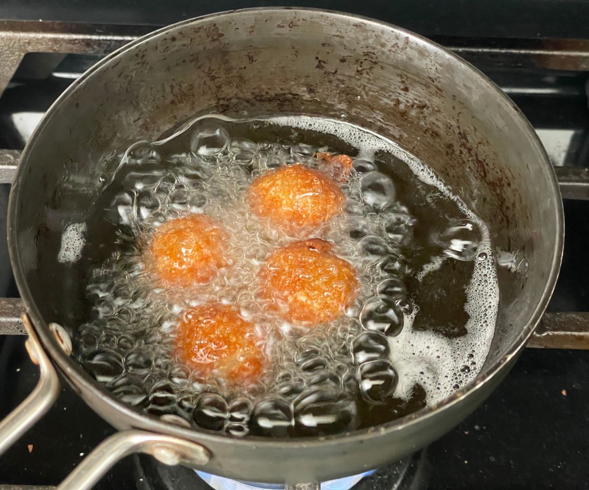 A pan is with fried vegan gulab jamuns.