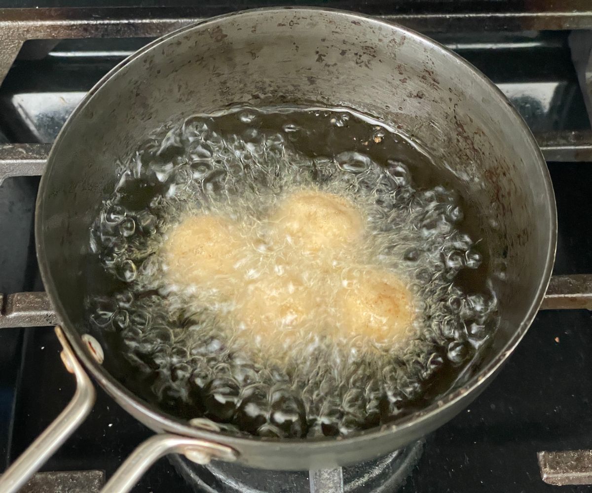 A pan is with hot oil and frying jamuns.