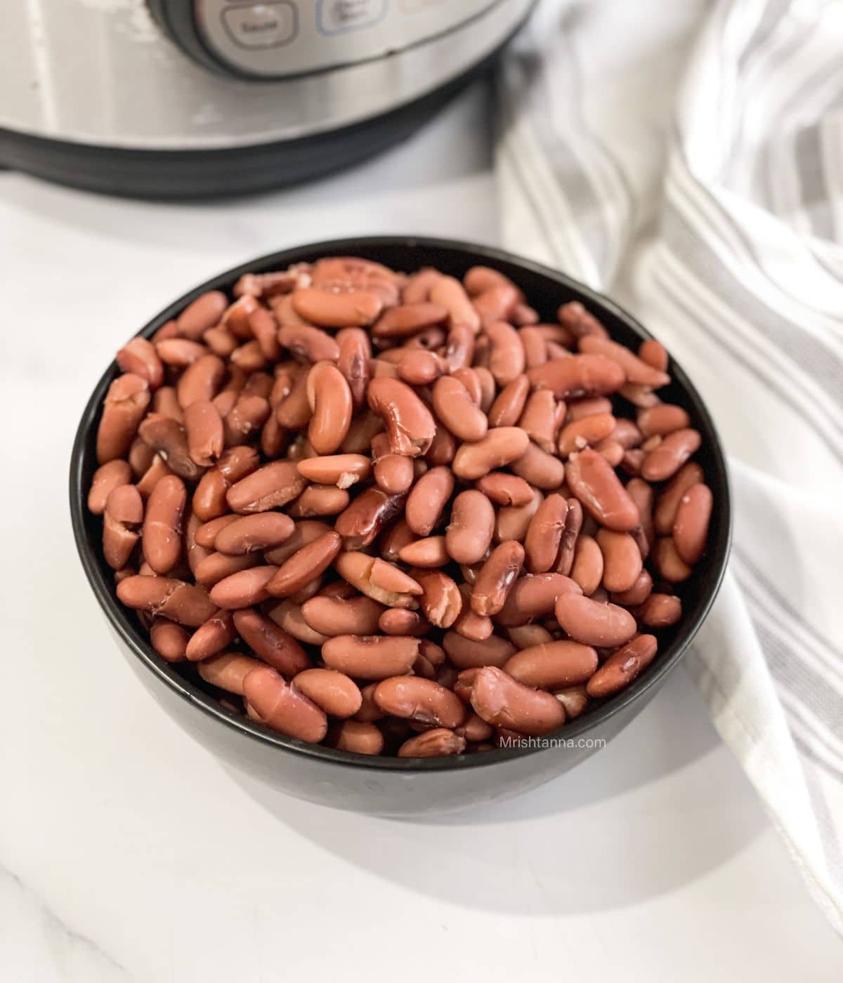 A bowl of cooked kidney beans are on the table near the Instant pot.