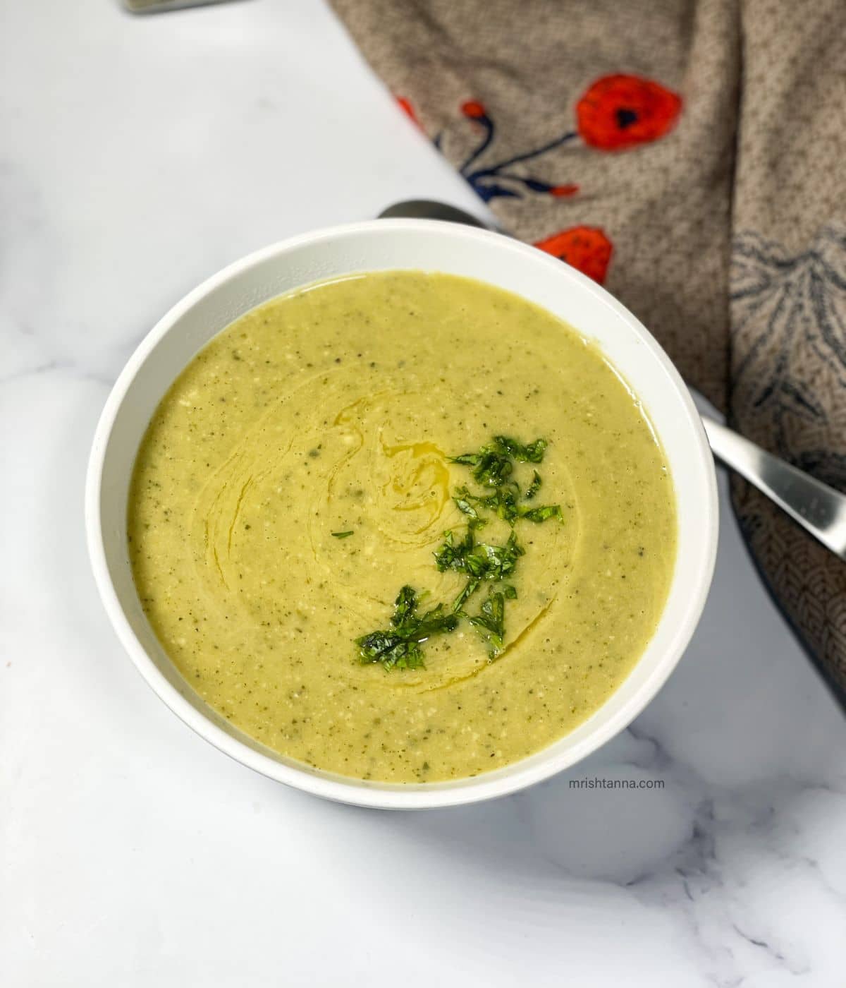 A bowl of zucchini soup is on the table.