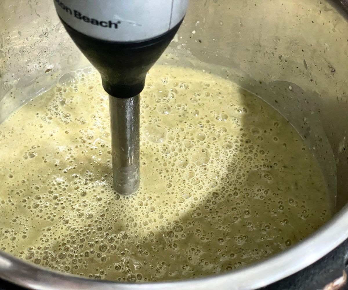 A pot is filled with creamy vegan zucchini soup.