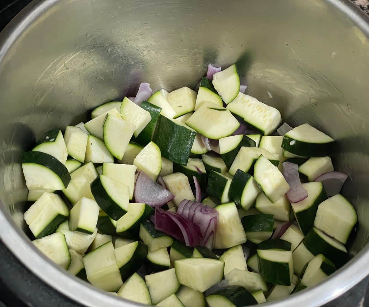 A pot is with zucchinis and onions for soup.