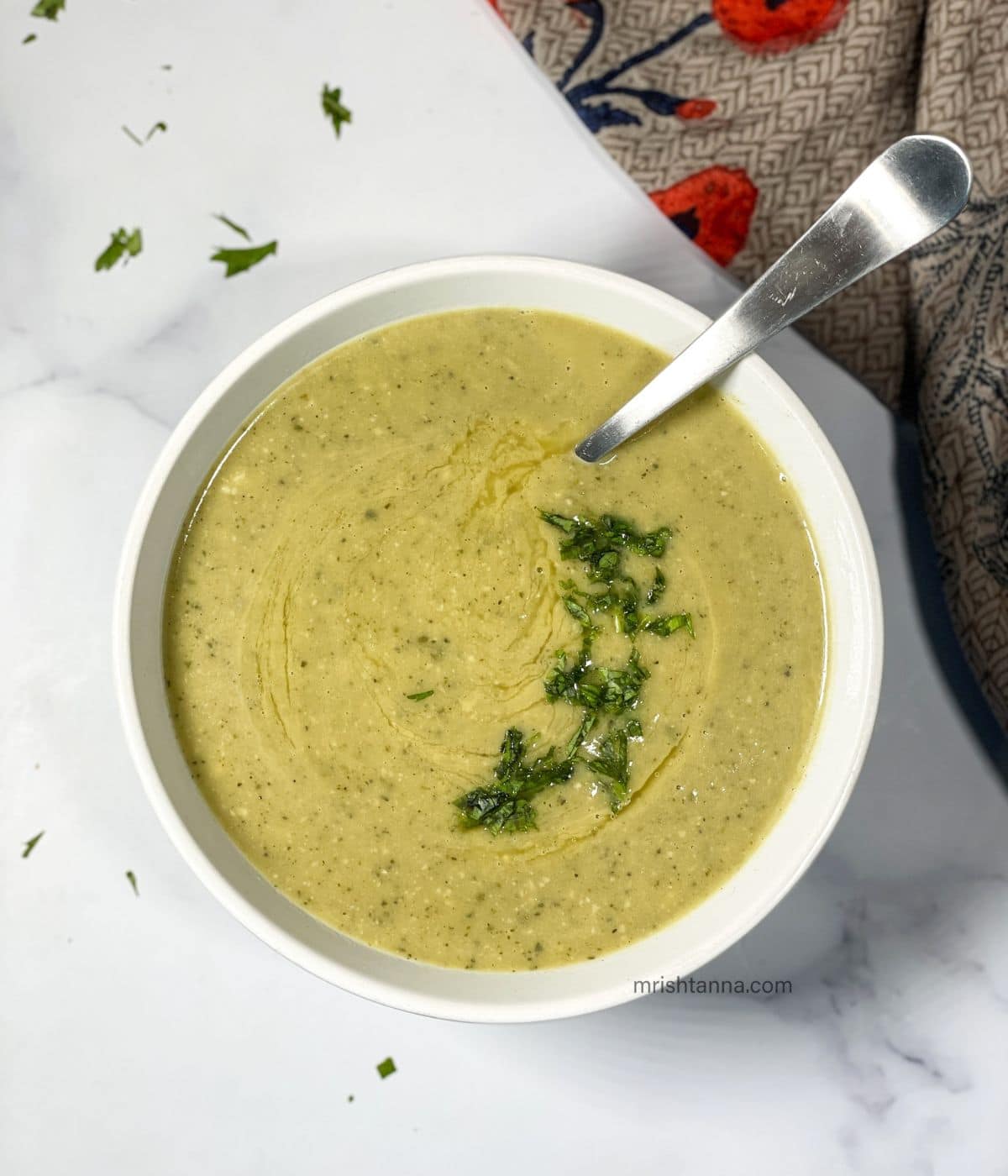 A bowl of Instant pot zucchini soup and a spoon is inserted.