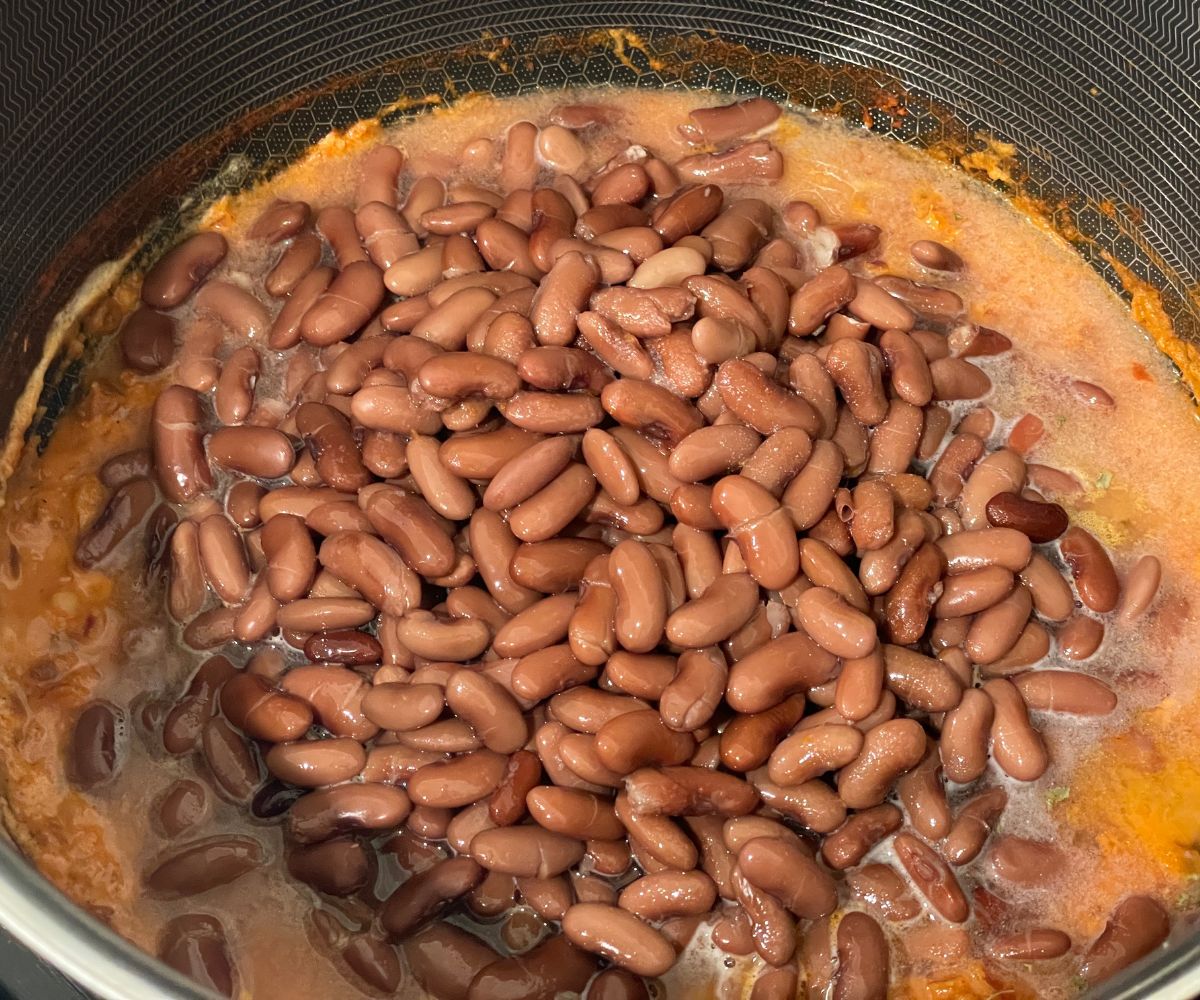 A pot is with masala and cooked kidney beans.
