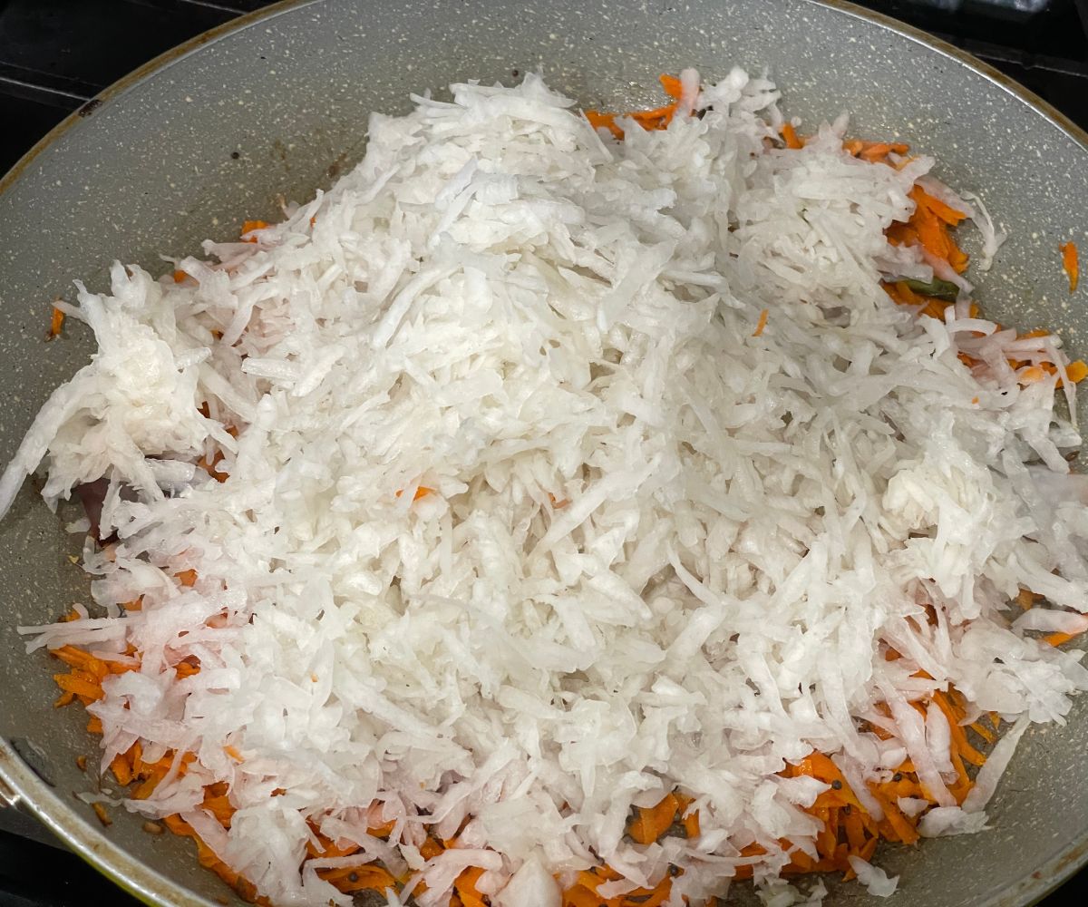 A pan is with radish and carrots over the heat.