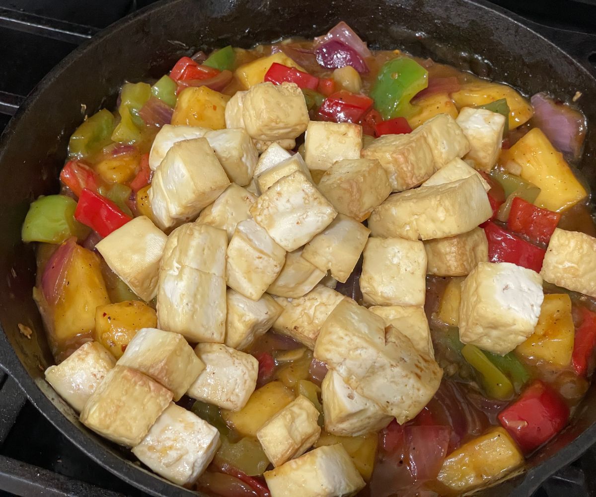 A pan is filled with pineapple tofu recipe over the heat.
