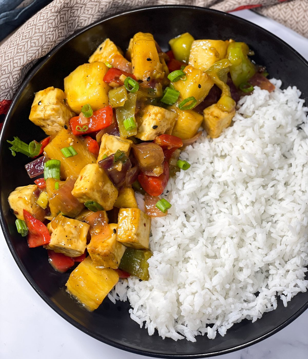 A plate is with pineapple tofu stir fry and white rice.