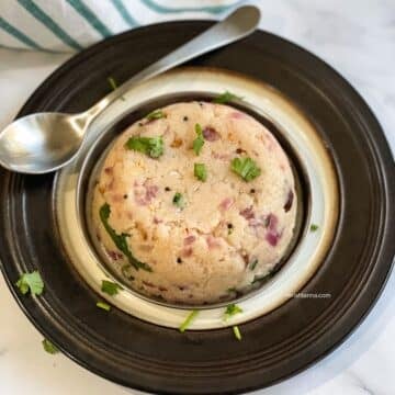 A plate of South Indian upma is on the table with a spoon.