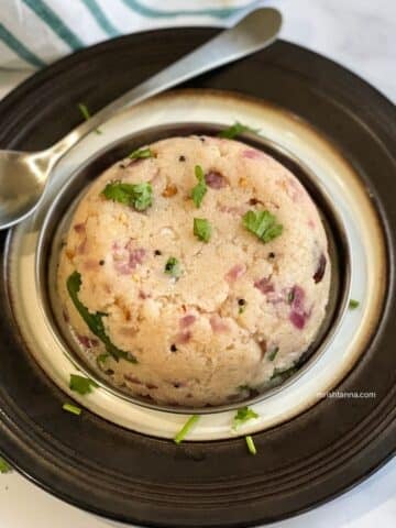 A plate of South Indian upma is on the table with a spoon.