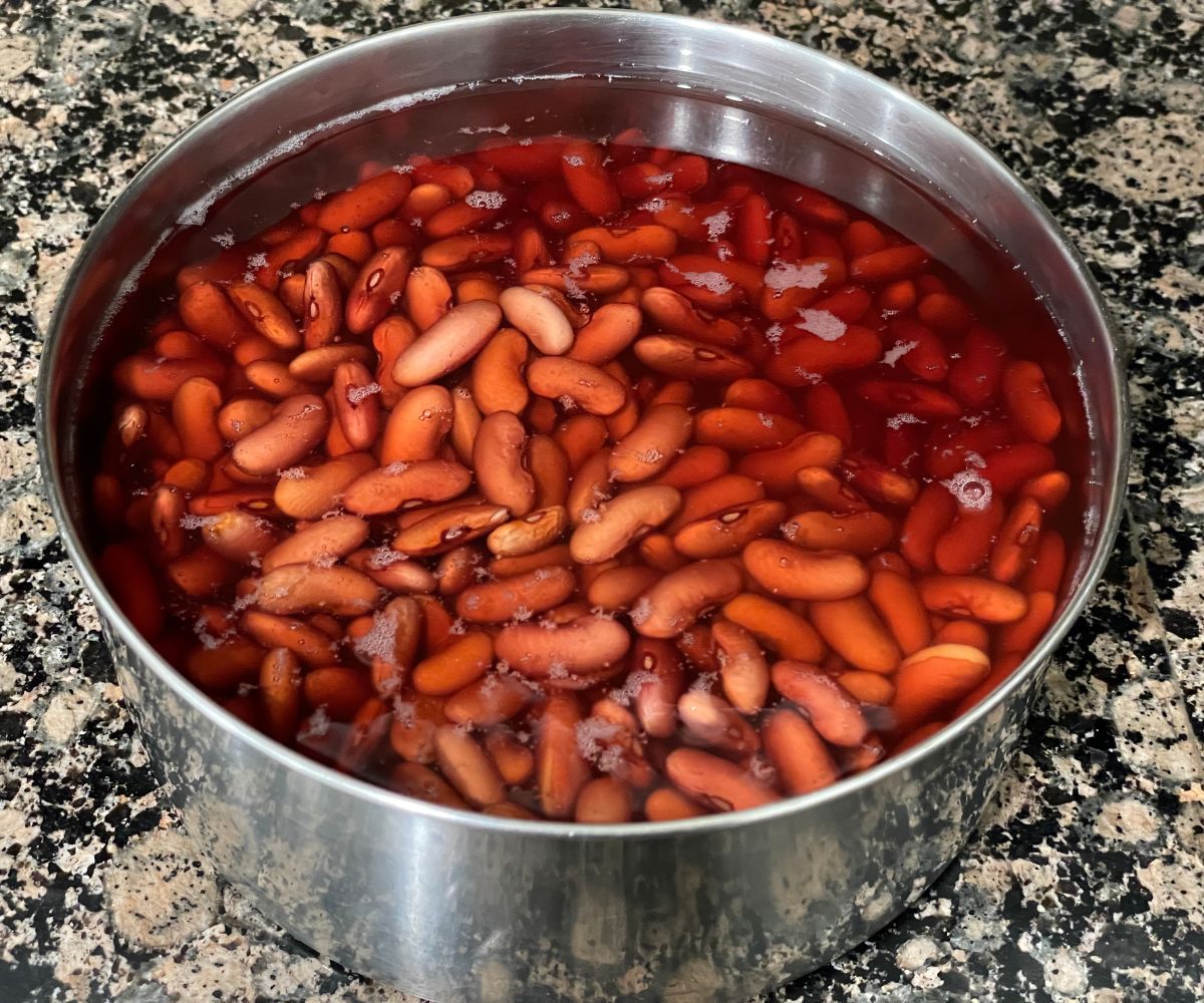 A bowl is with water and soaked kidney beans on the counter top.