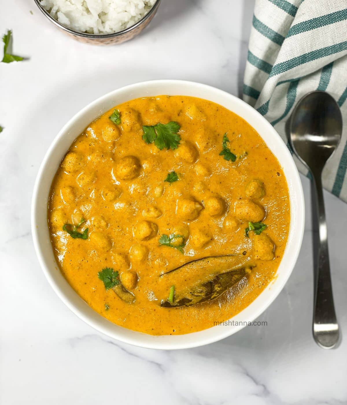 A bowl of south Indian chana masala is on the surface.