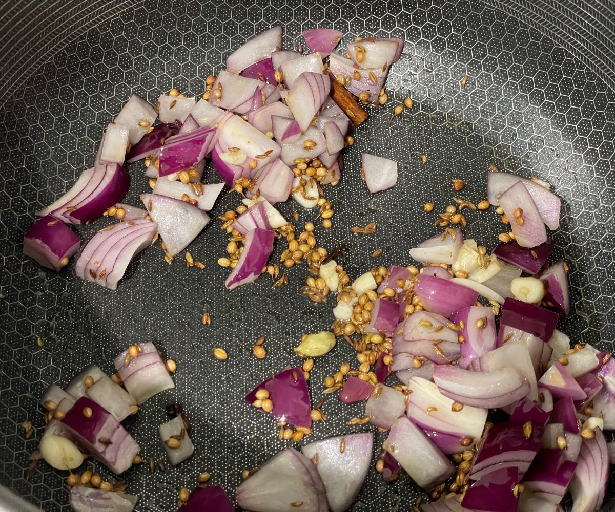 A pan is with spices and chopped onions.