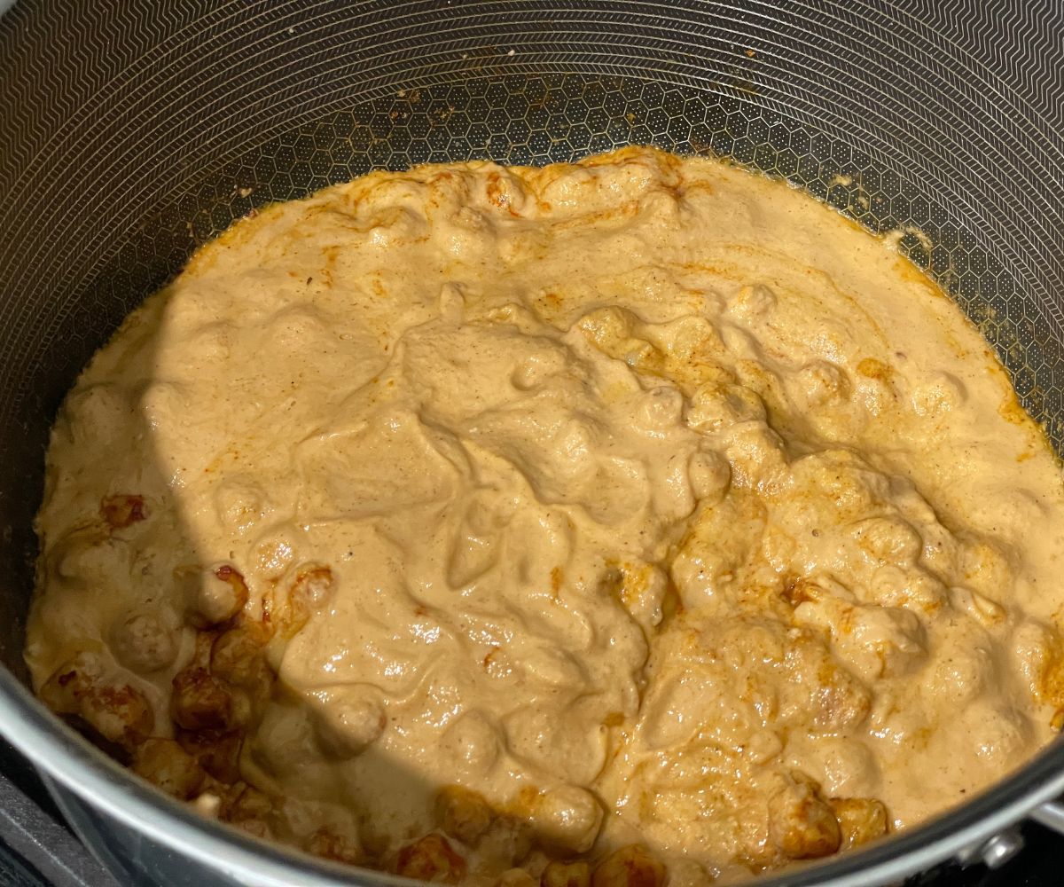 A pan is with chana masala sauce and chickpeas.