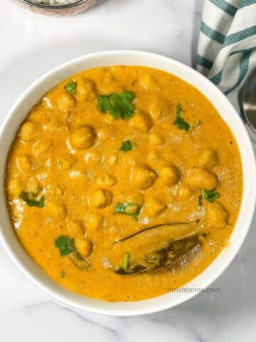 A bowl of South Indian chana masala is on the table.