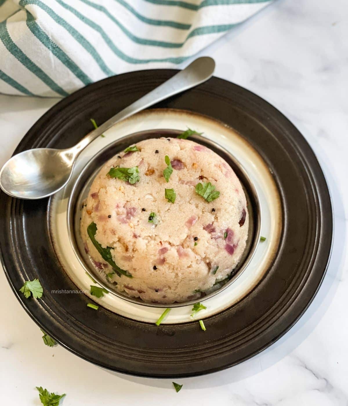 A plate is with rava upma and a spoon by the side.