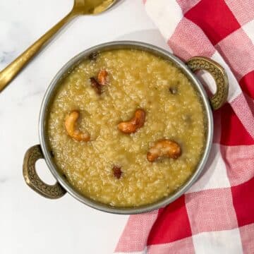 A bowl of sweet pongal is on the surface with a golden spoon.
