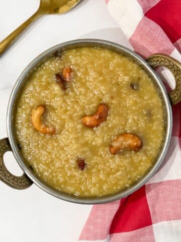 A bowl of sweet pongal is on the surface with a golden spoon.