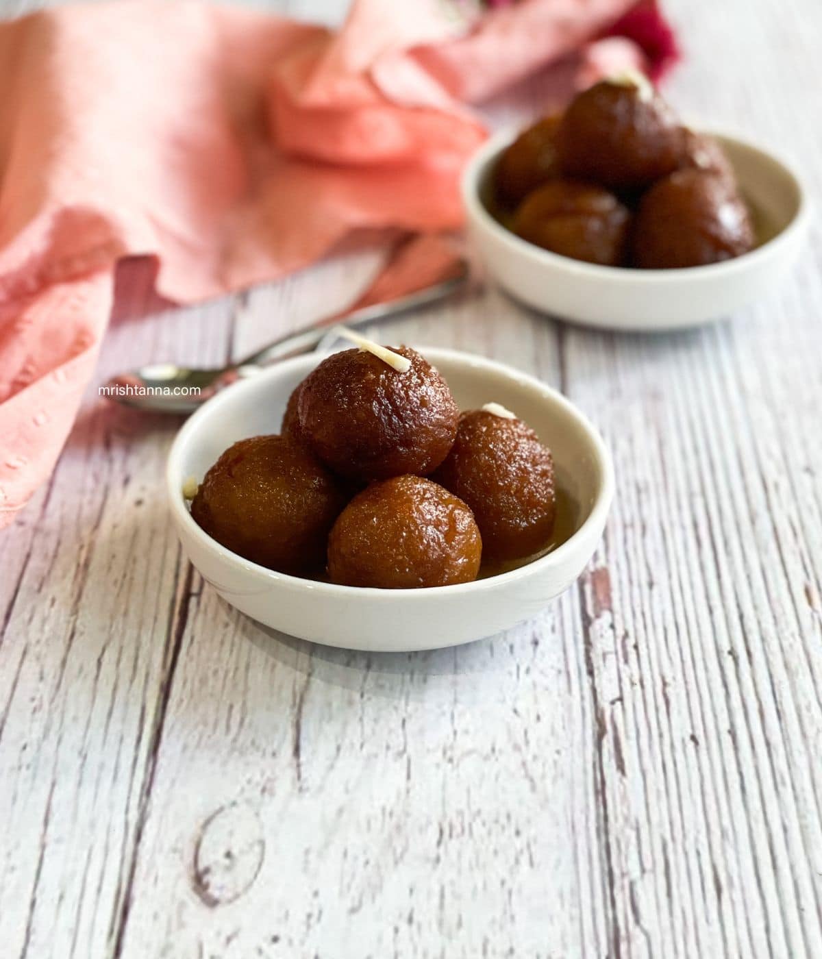 A bowl of vegan gulab jamun is on the table.
