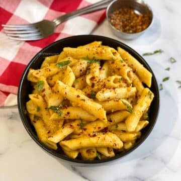 A bowl of vegan pumpkin flavored pasta is on the table.