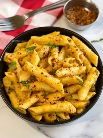 A bowl of vegan pumpkin flavored pasta is on the table.