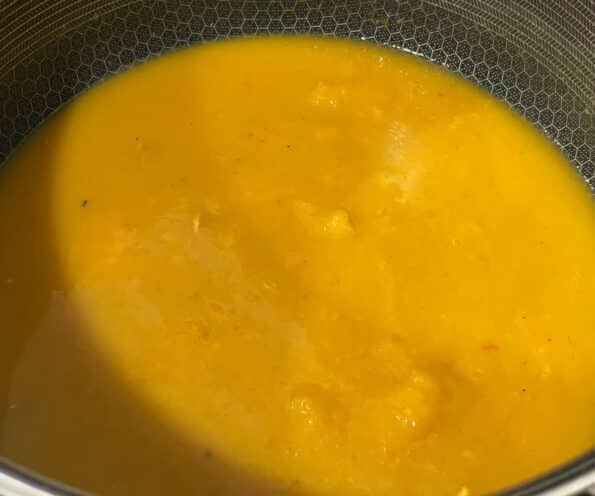 A sauce pan is with pumpkin puree and vegetable broth on the flame.