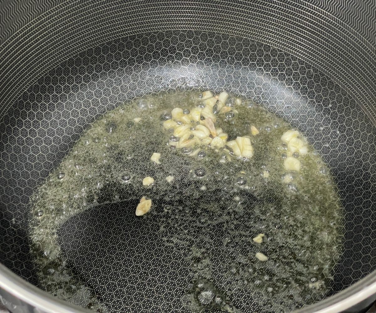 A pot is with vegan butter and chopped garlic over the stove top.