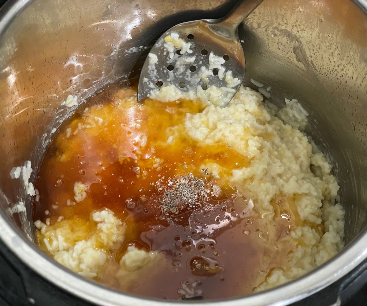 An instant pot is with rice mixture and jaggery syrup.