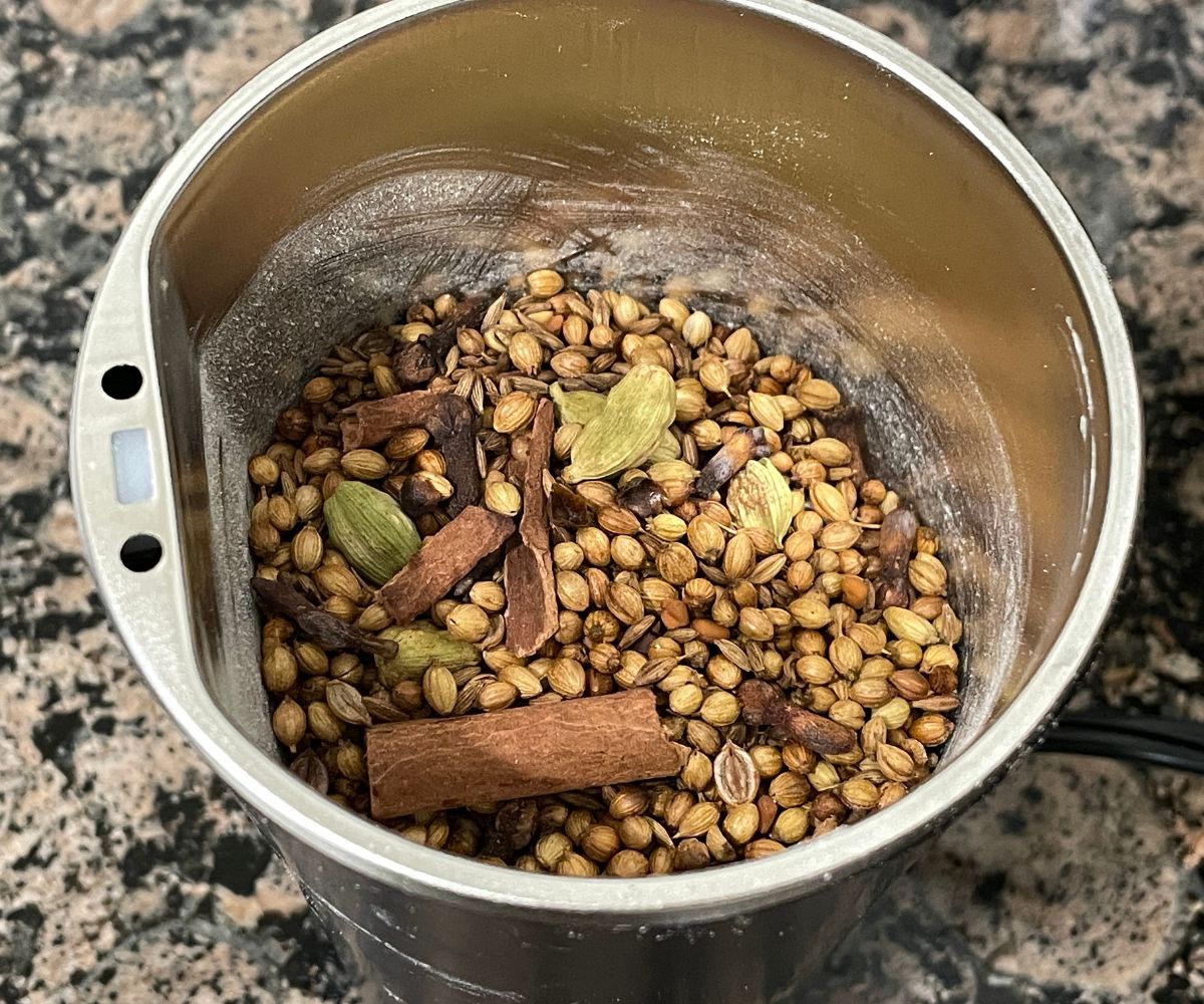 A coffee grinder is with roasted whole spices.