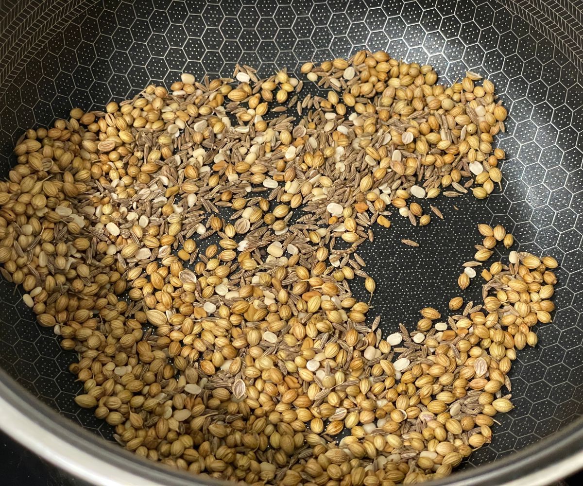 A pan is with all the spices for curry powder over the heat.