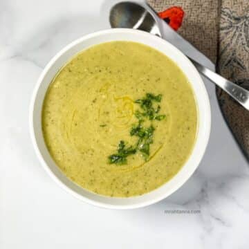 Zucchini soup is in a bowl topped with parsley.
