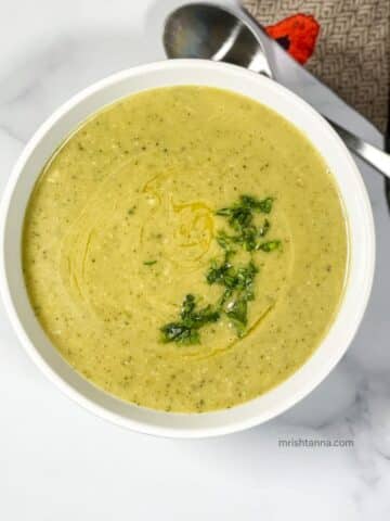 Zucchini soup is in a bowl topped with parsley.